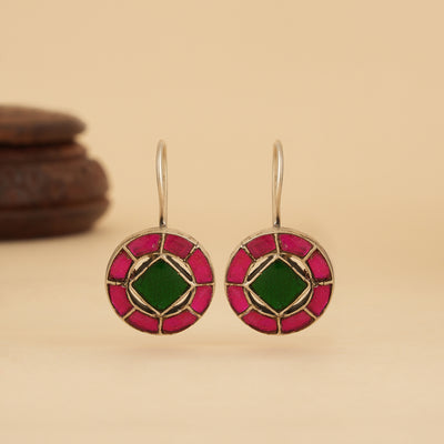 Pair of kundan earrings with pink and green design on a beige background
