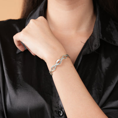 Silver bracelet on a person's wrist against a black satin background
