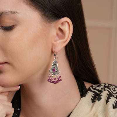 A model wearing Oxidised silver earrings with intricate detailing and hanging ruby beads